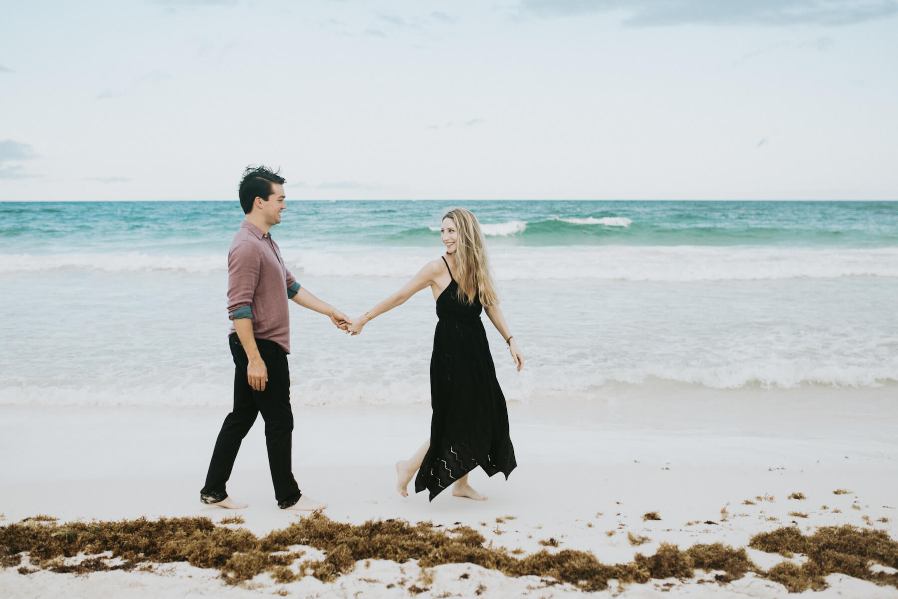 couple holding hands walking down the beach in Tulum, Mexico