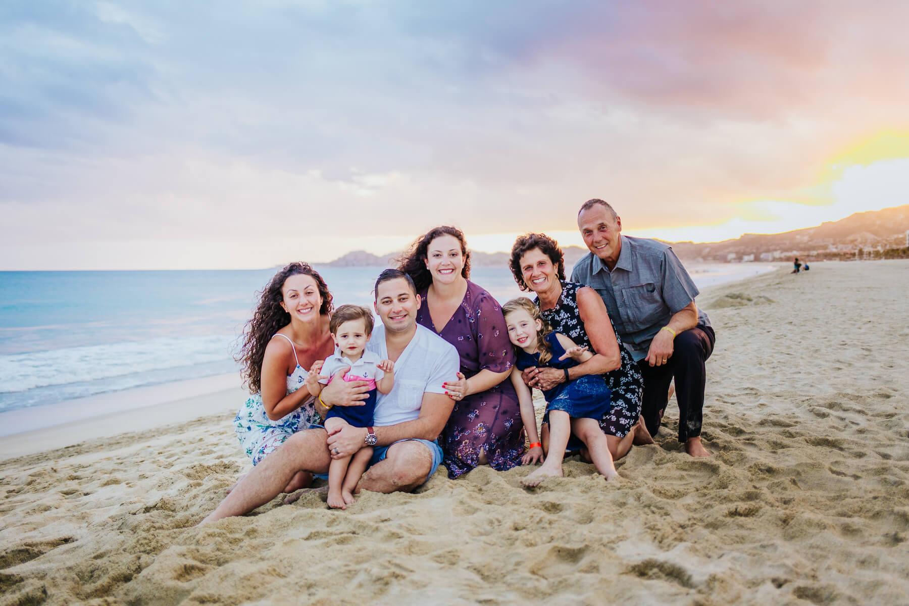 Family with kids and grandparents sitting on the beach in Cabo San Lucas, Mexico