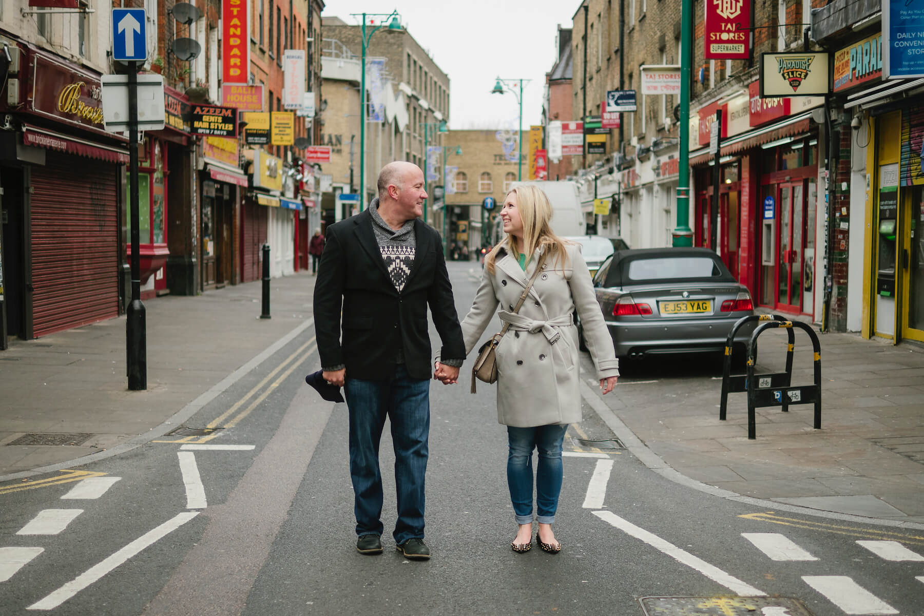 a couple holding hands and looking at each other in the middle of the street in London, England