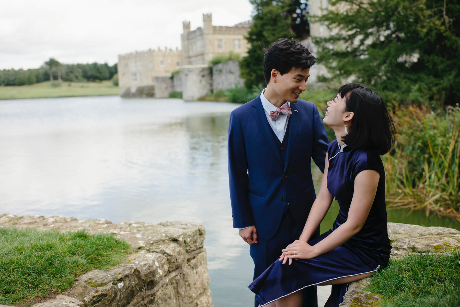 Couples trip near Leeds castle, they're sitting down with the castle in the background in London, England