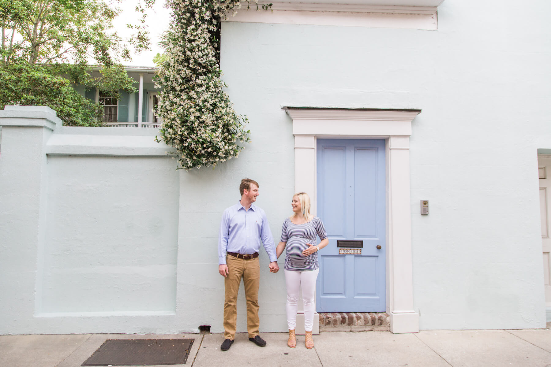 Couple standing looking at each other, the woman is pregnant and touching her belly in Charleston, South Carolina 