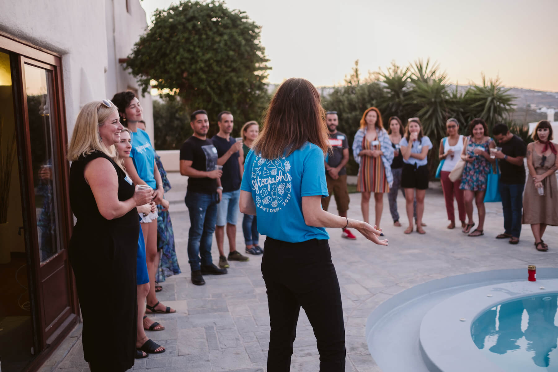 A group of people talking around a pool in Santorini, Greece