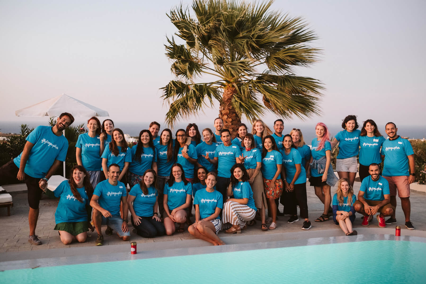 Group of people in blue t-shirts standing by a pool in Santorini, Greece