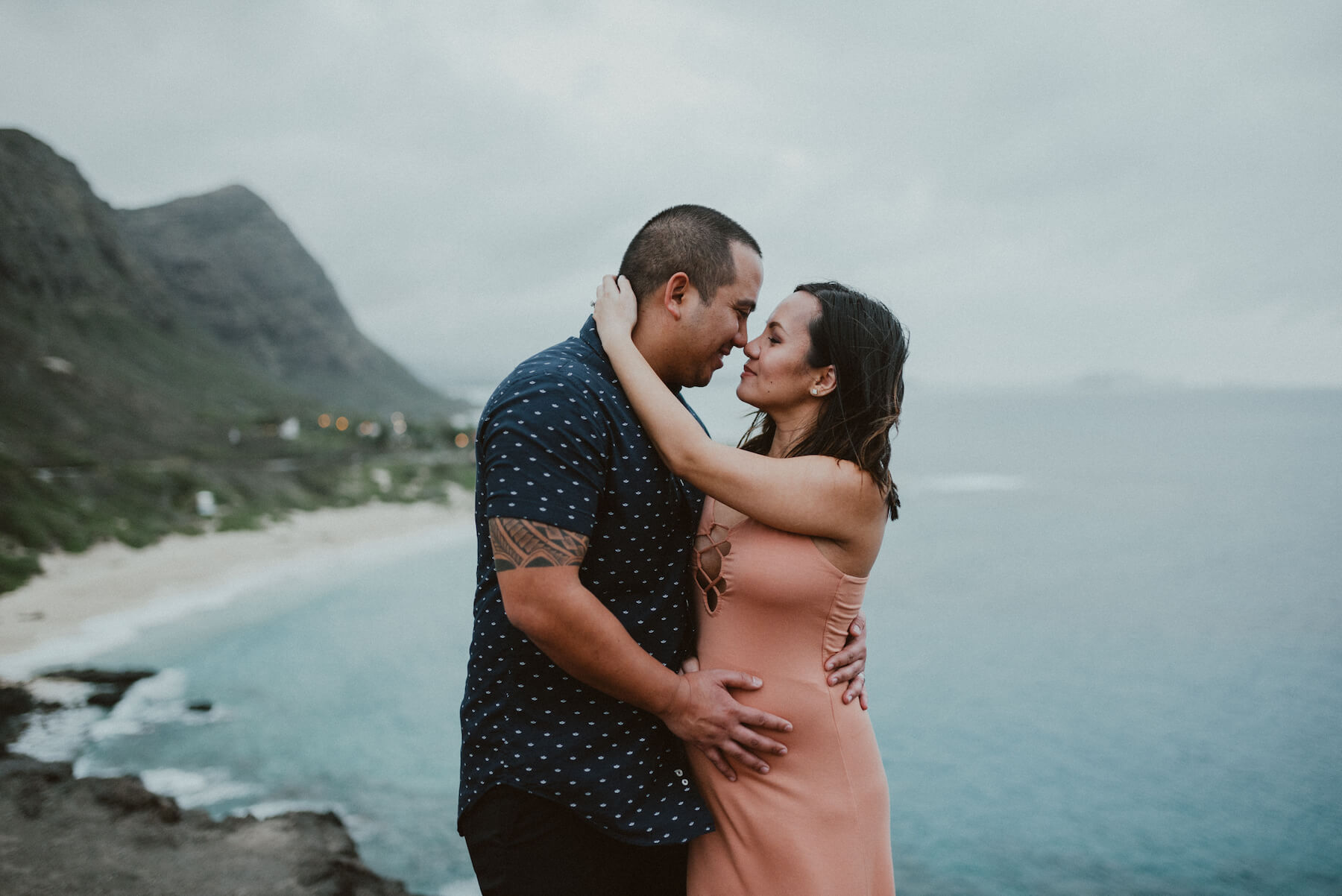 Couple pregnant holding each other, with the ocean in the background in Honolulu, Hawaii
