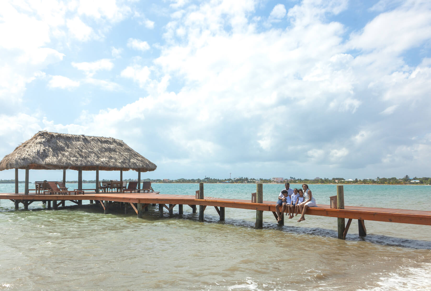 Family sitting on a dock in Placencia Belize