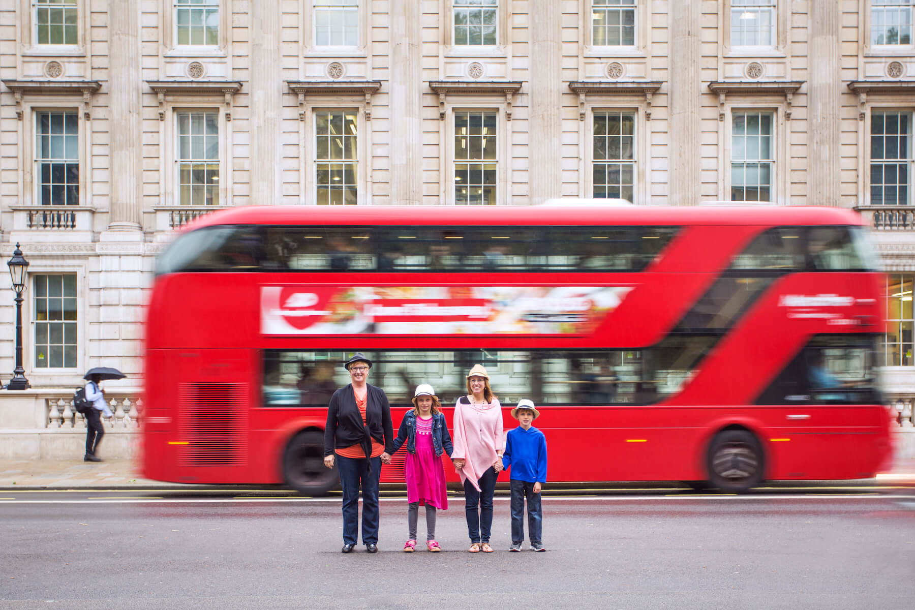 family in front of a double decker bus in London, England