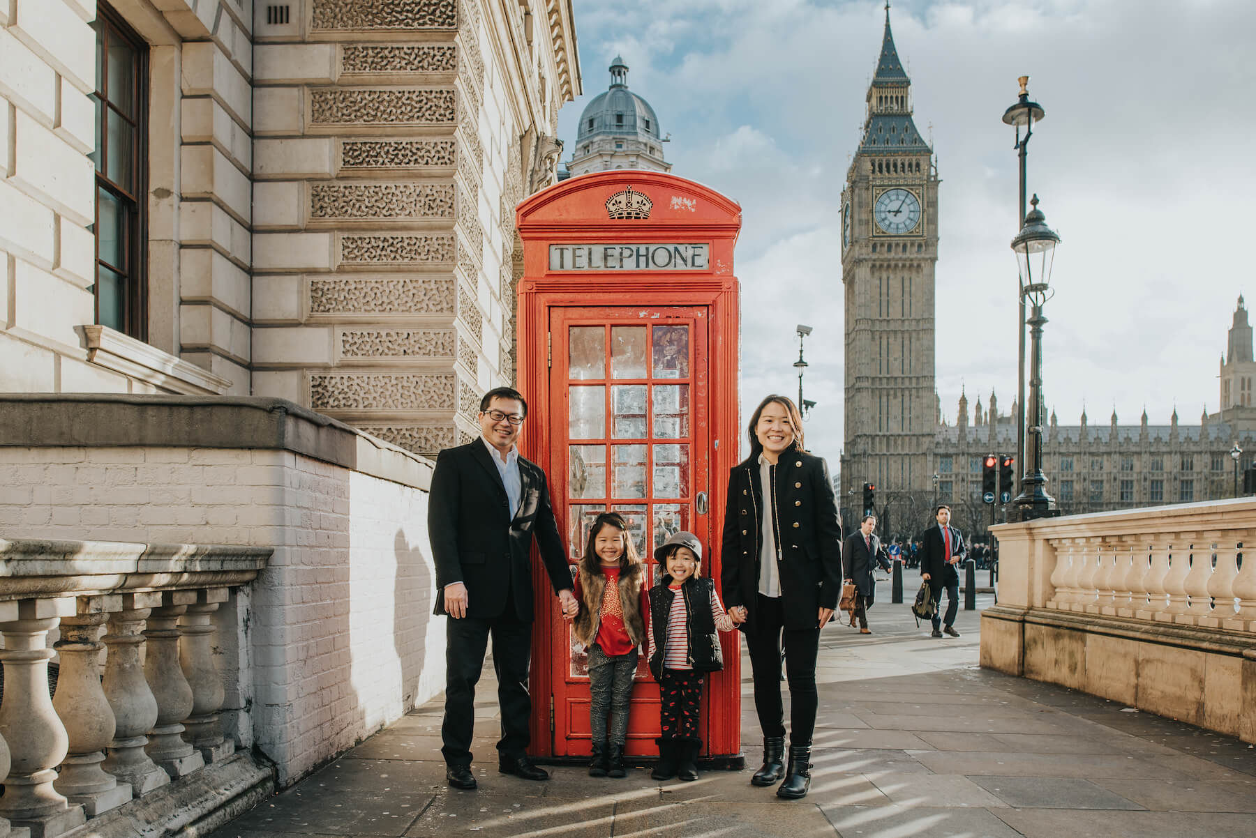 family standing in front of a red phone booth in London, England