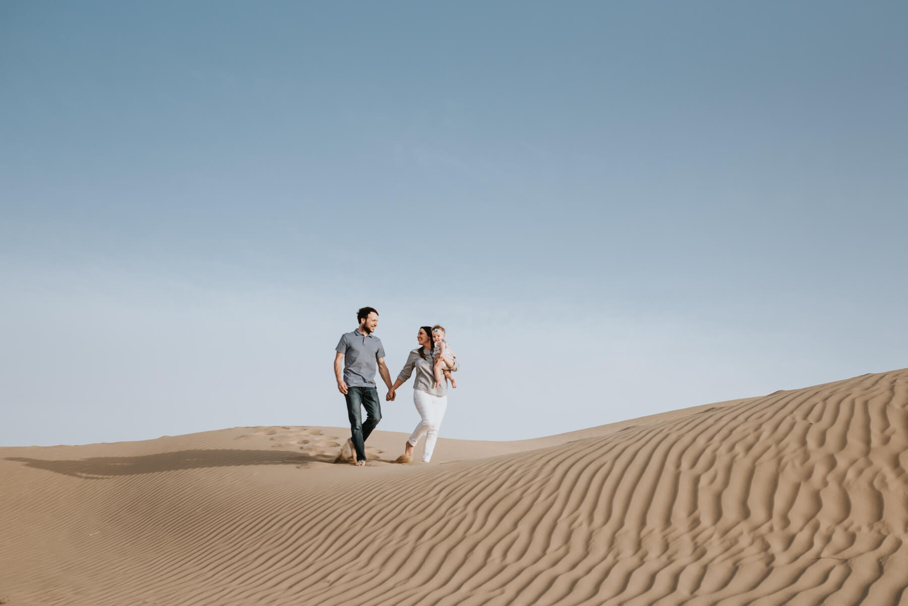 Family in Dubai walking in the desert holding a baby in Dubai, UAE