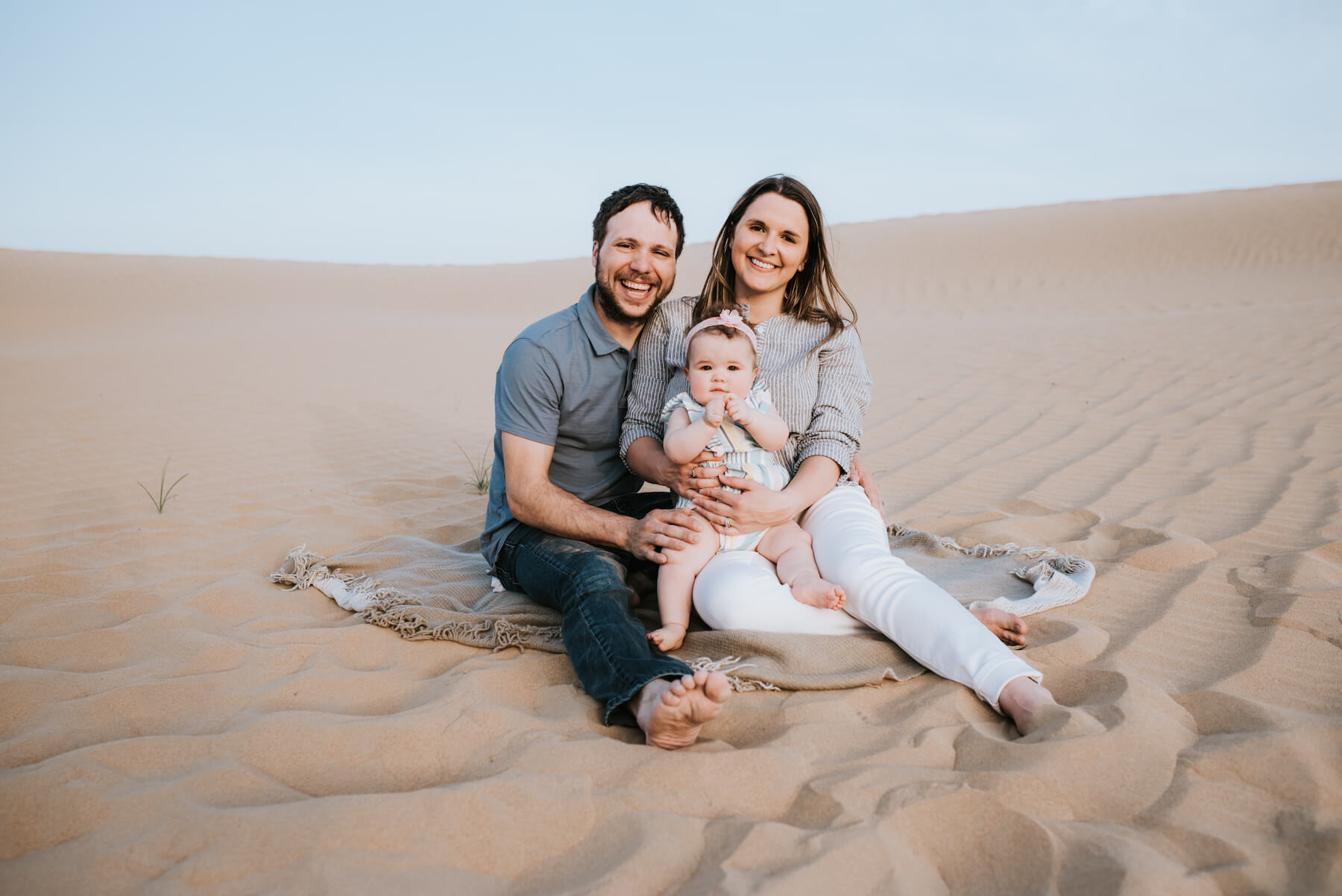 Family sitting on the sand holding a baby in the desert in Dubai, UAE