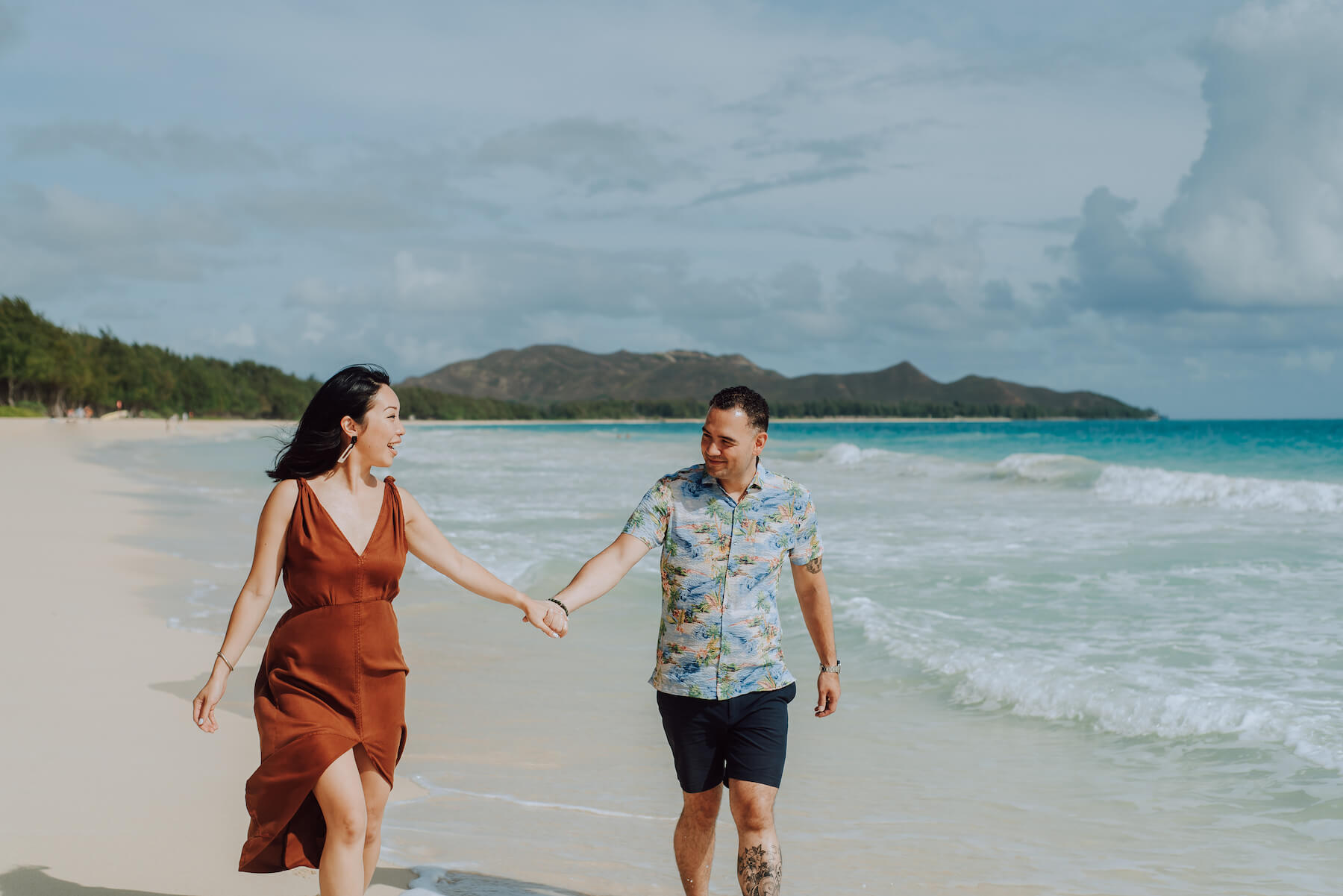 A couple holding hands and walking on the beach in Honolulu, Hawaii