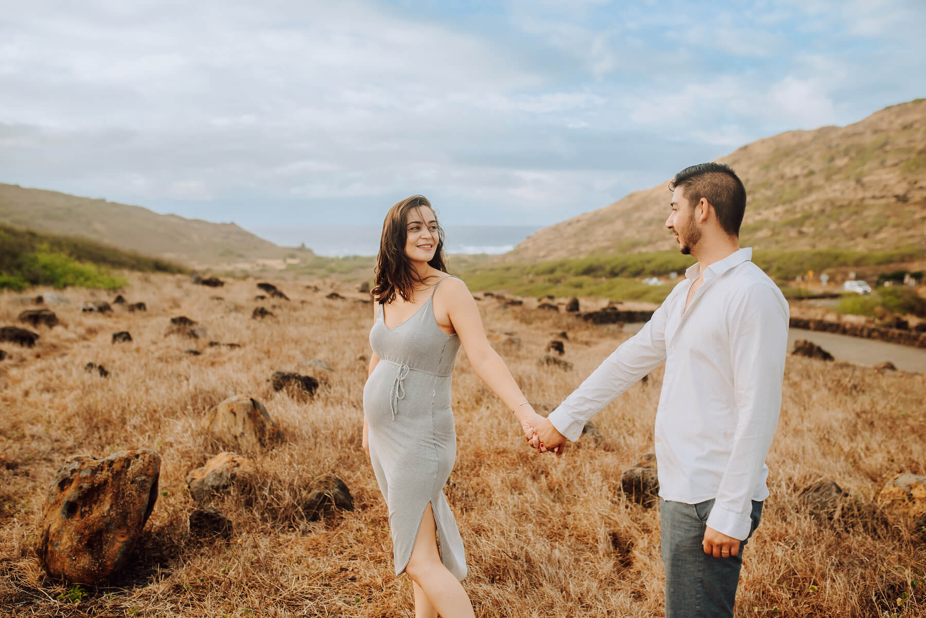 A couple looking at each other, the woman is expecting and they're on a babymoon vacation in Honolulu, Hawaii