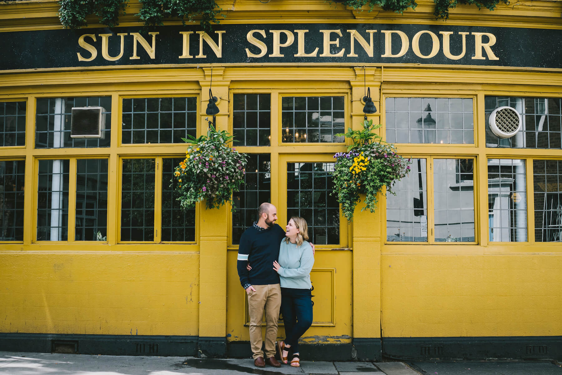 Couple standing in front of Sun in Splendour pub in London, England