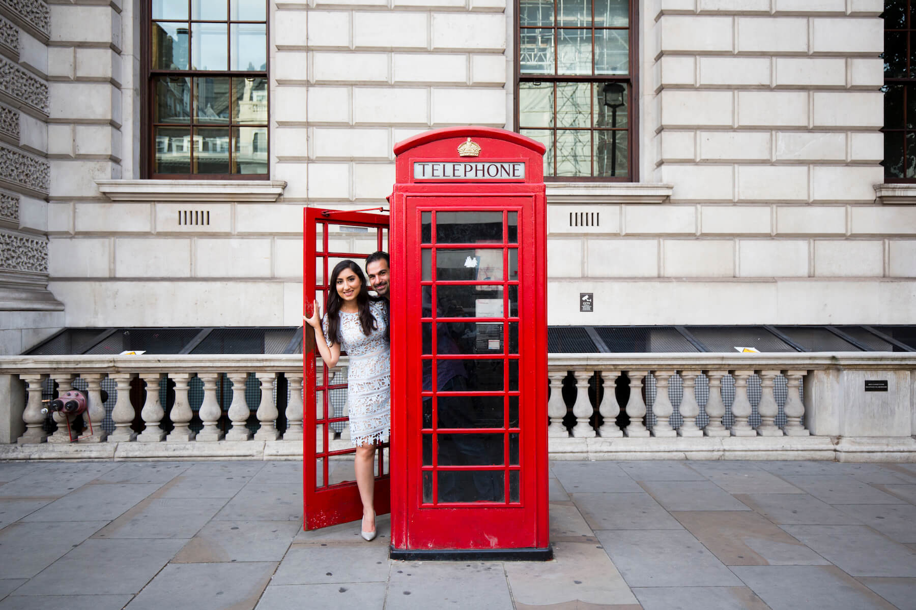 A couple looking out of the phone booth, having fun in London, England