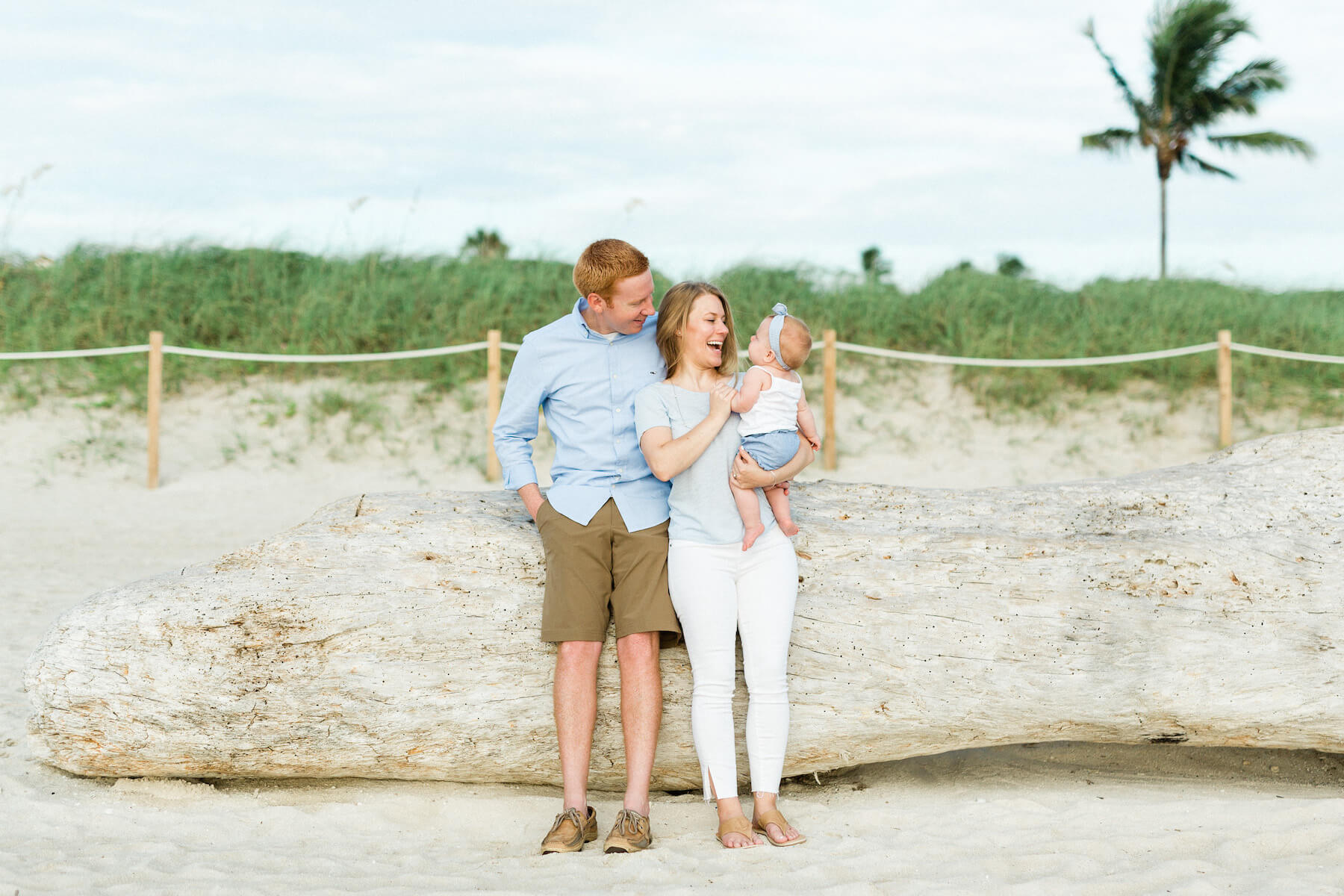 family with a baby standing on the sidewalk near the beach in Miami, Florida