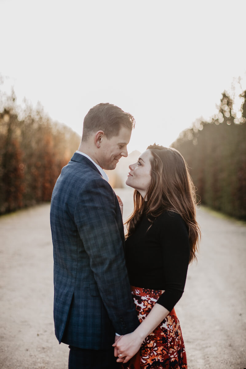 A couple smiling and holding each other on Versailles palace grounds, Paris, France