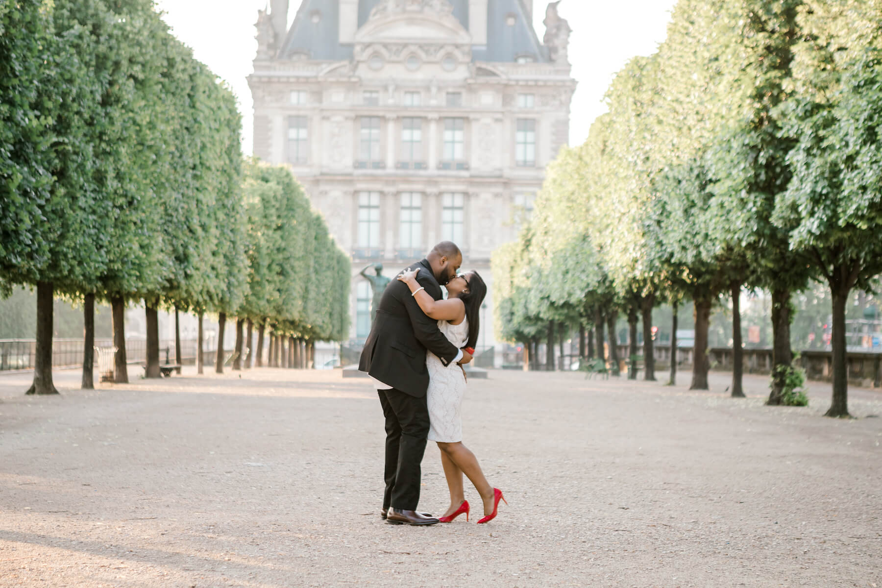 A couple kissing after a wedding proposal in Louvre grounds in Paris, France