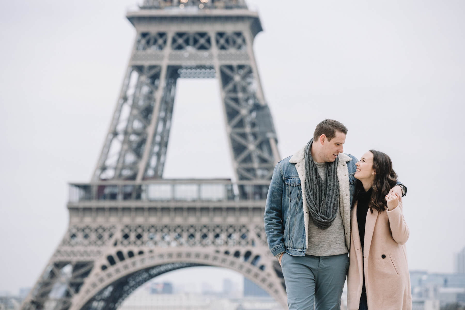 A couple holding each other and walking in front of the Eiffel tower in Paris, France