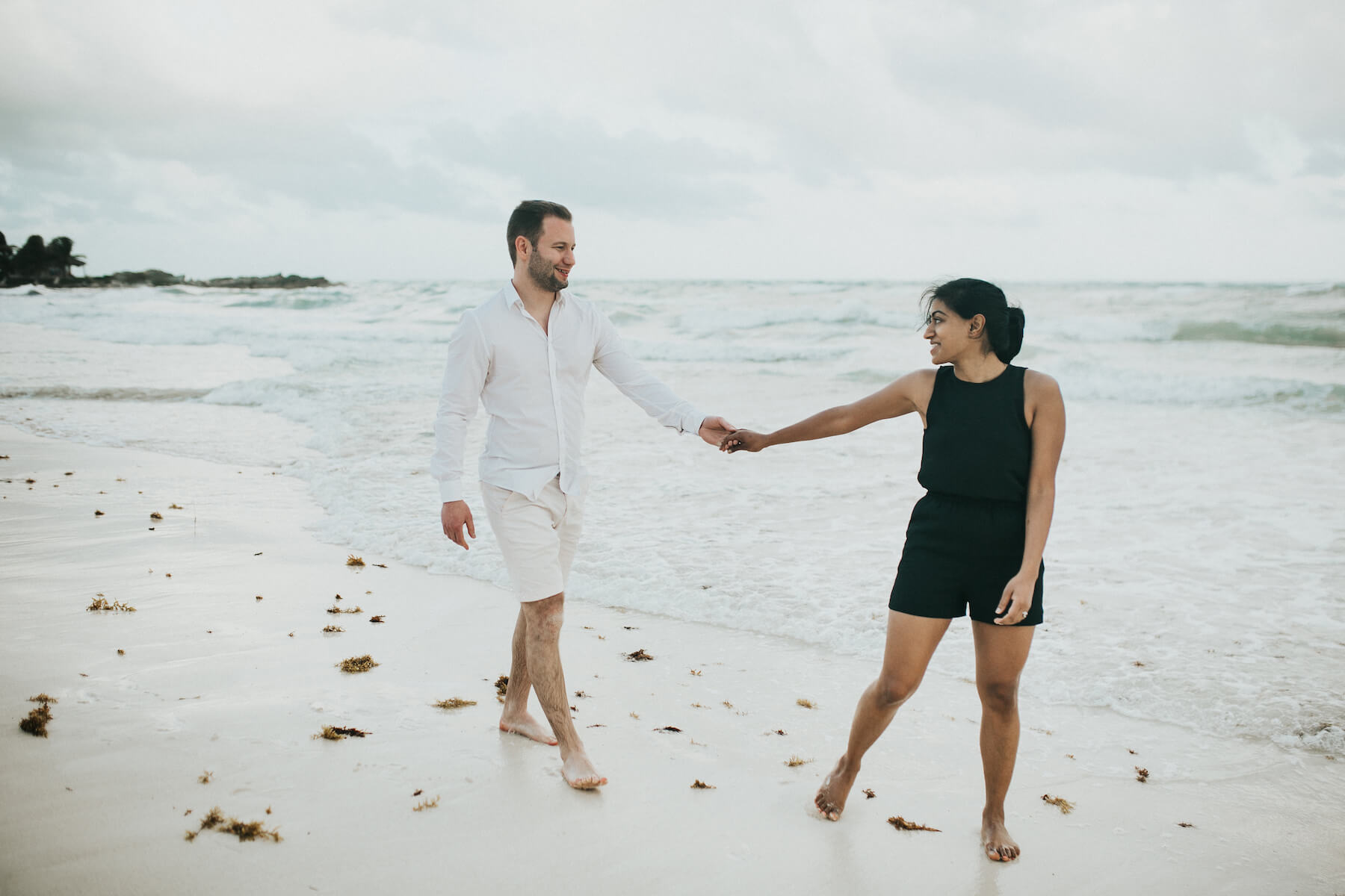 couple holding hands and looking at each other on the beach in Tulum, Mexico
