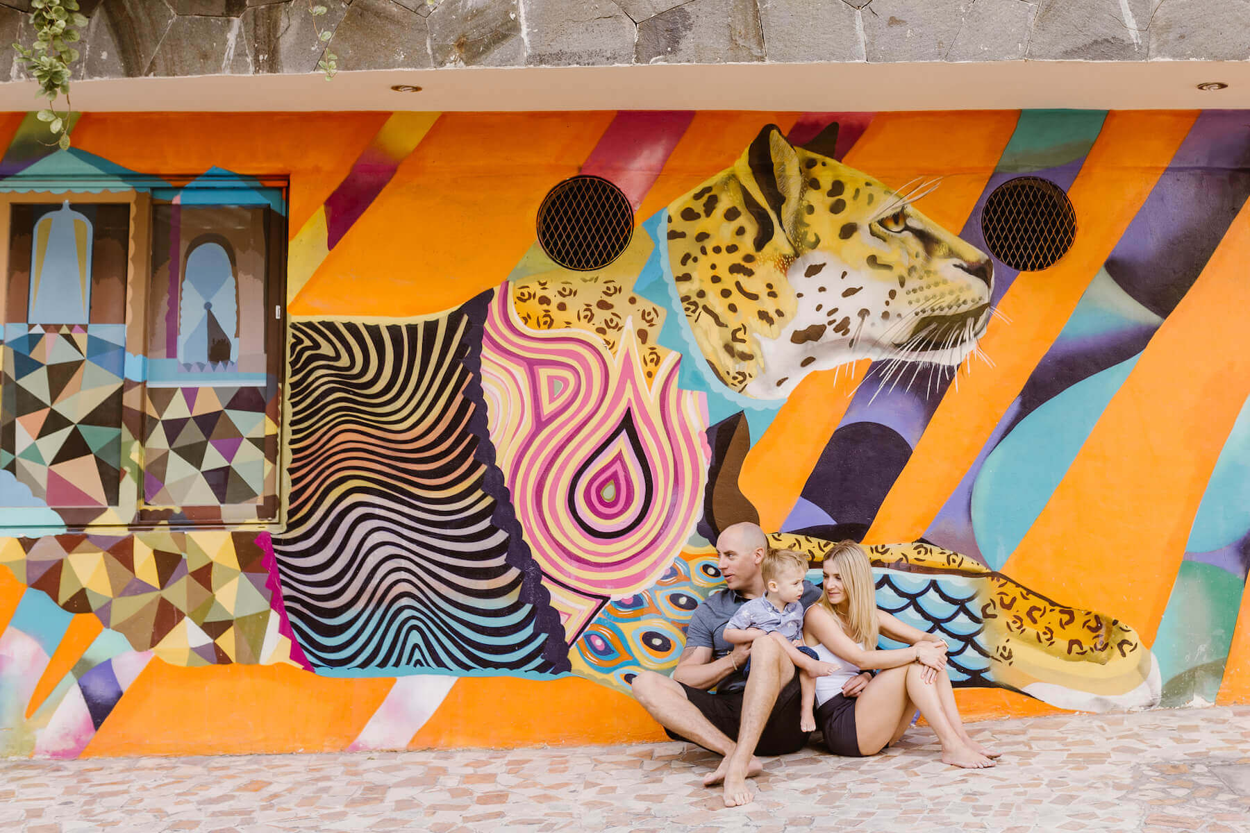 family in sitting down in front of a colourful painted wall in Playa del Carmen, Mexico