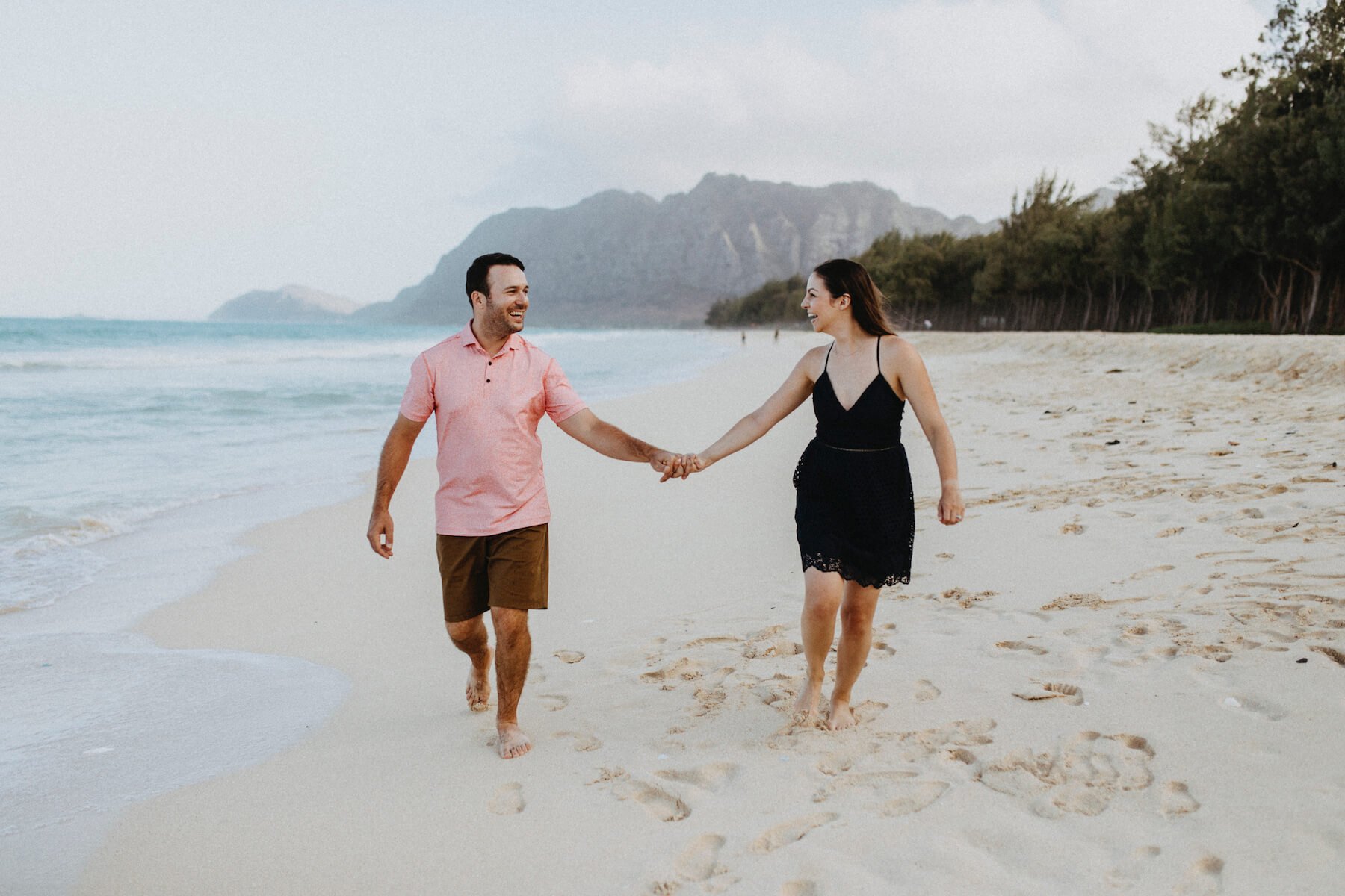  A couple holding hands and walking on the beach in Honolulu, Hawaii