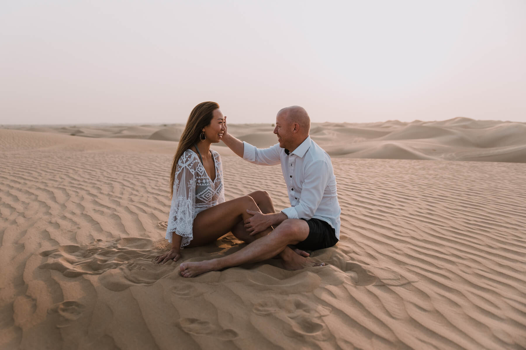 couple sitting in Dubai desert facing each other, Dubai, UAE