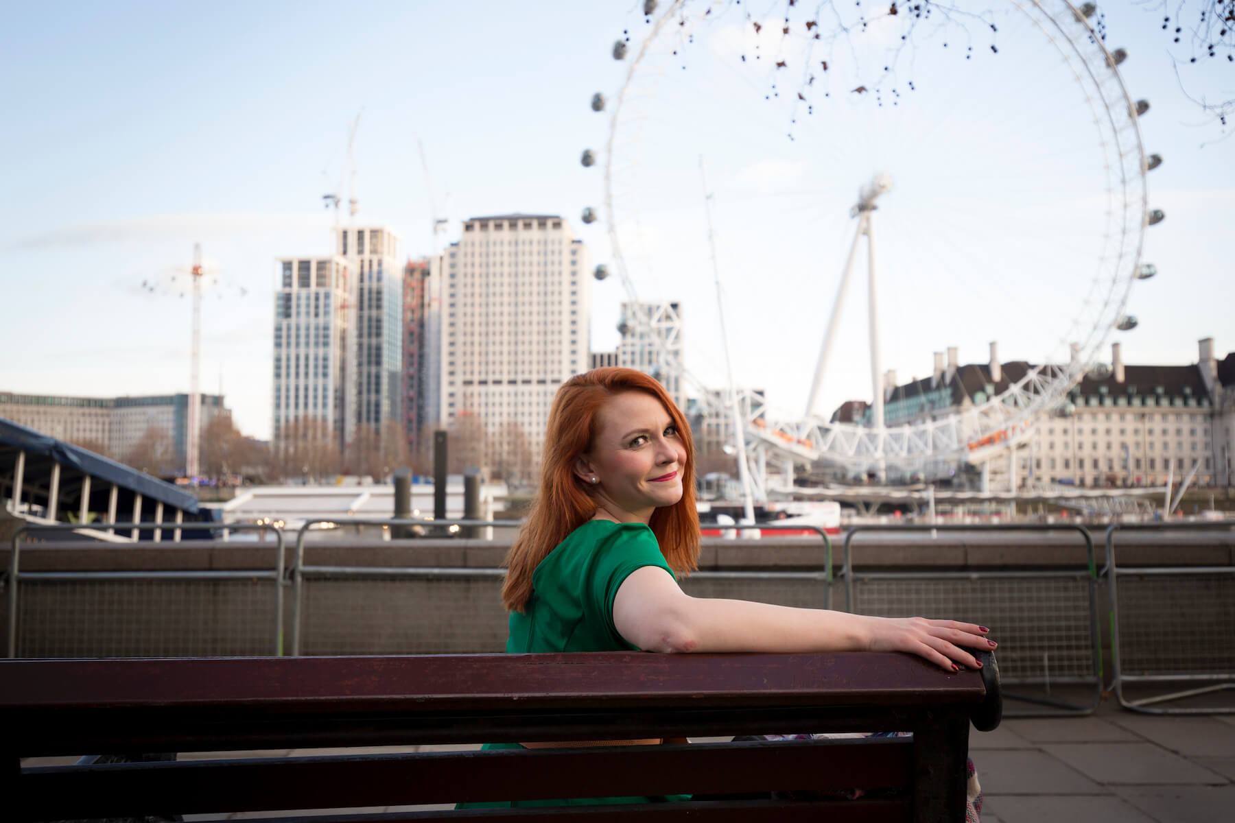 solo traveller sitting on a bench with the London Eye in the background in London, England