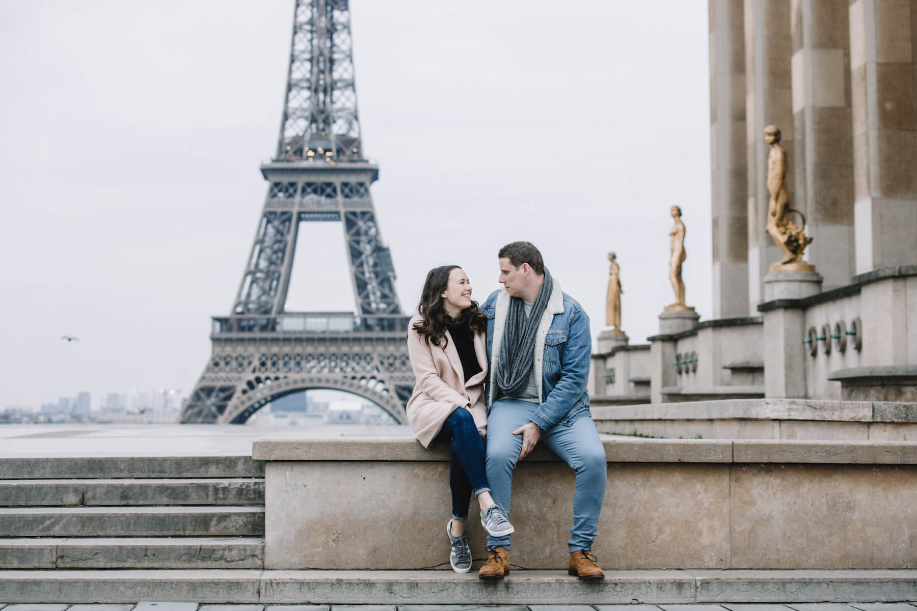 a couple sitting and laughing near the Eiffel tower in Paris, France