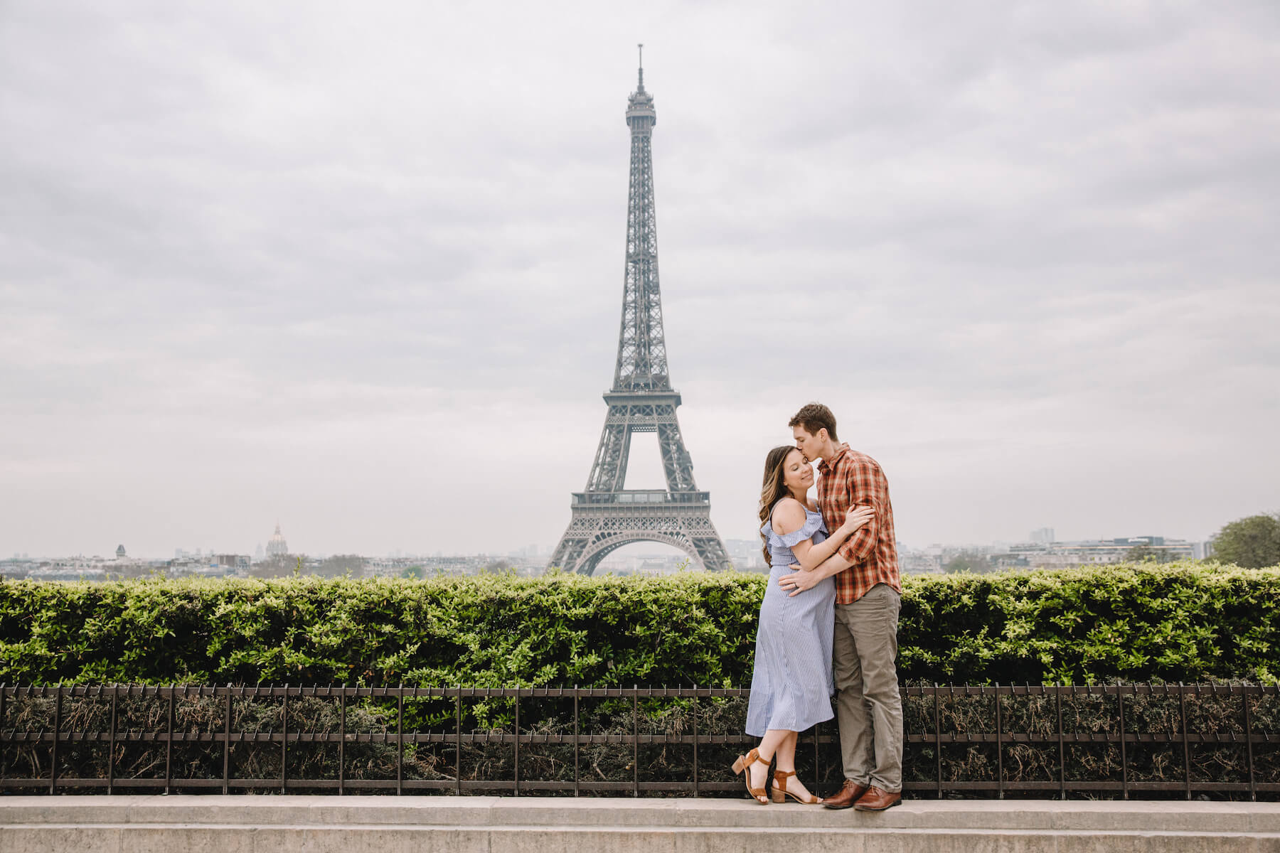 Couple hugging, the woman is pregnant, standing in front of the Eiffel Tower in Paris, France