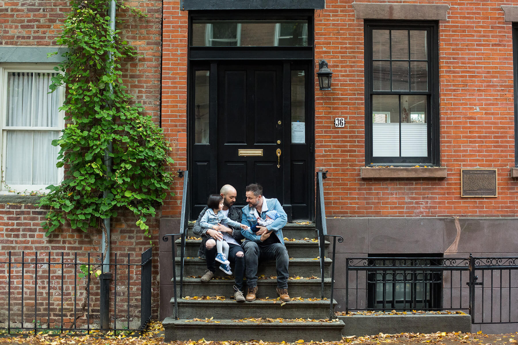 family of four sitting on the steps of a brownstone in New York City, New York