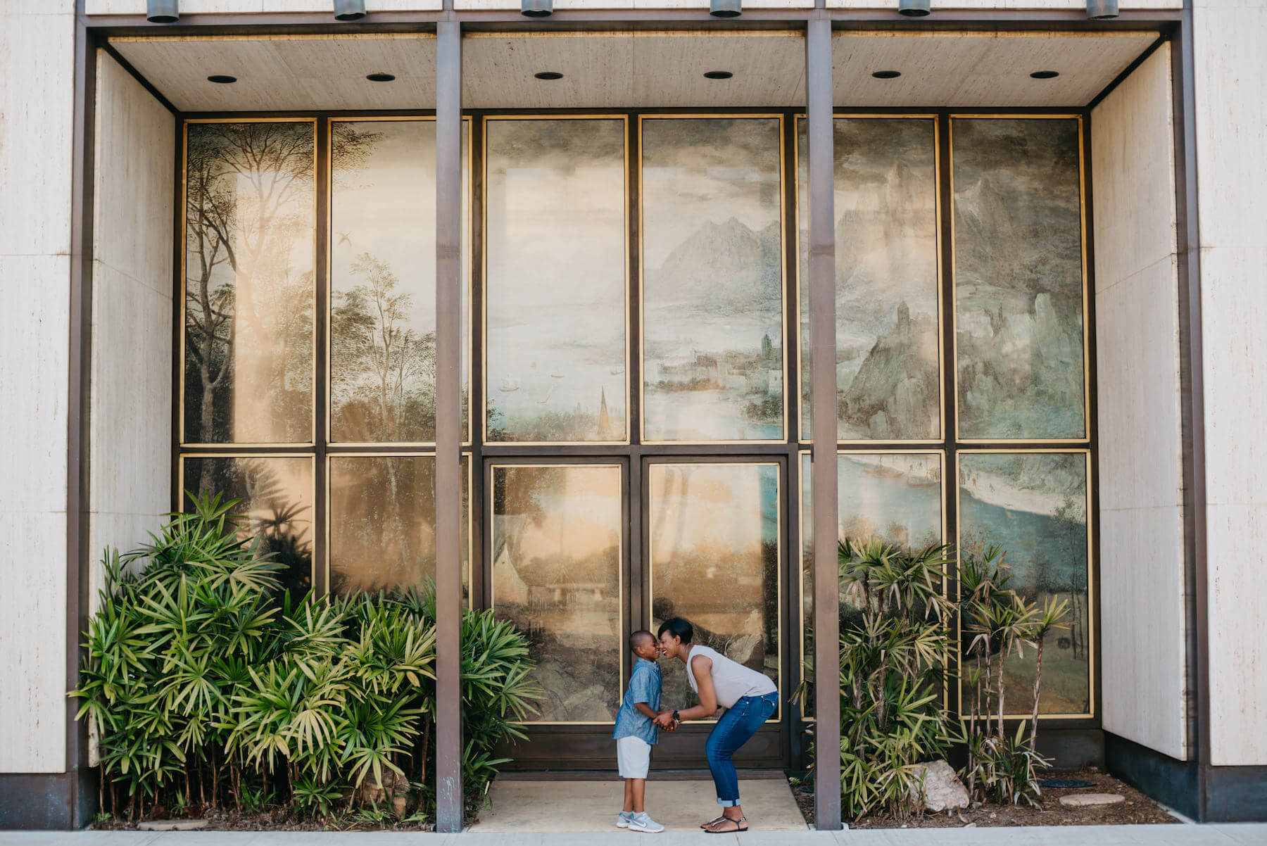 mother and son having fun, looking at each other in front of a large window in San Diego, California
