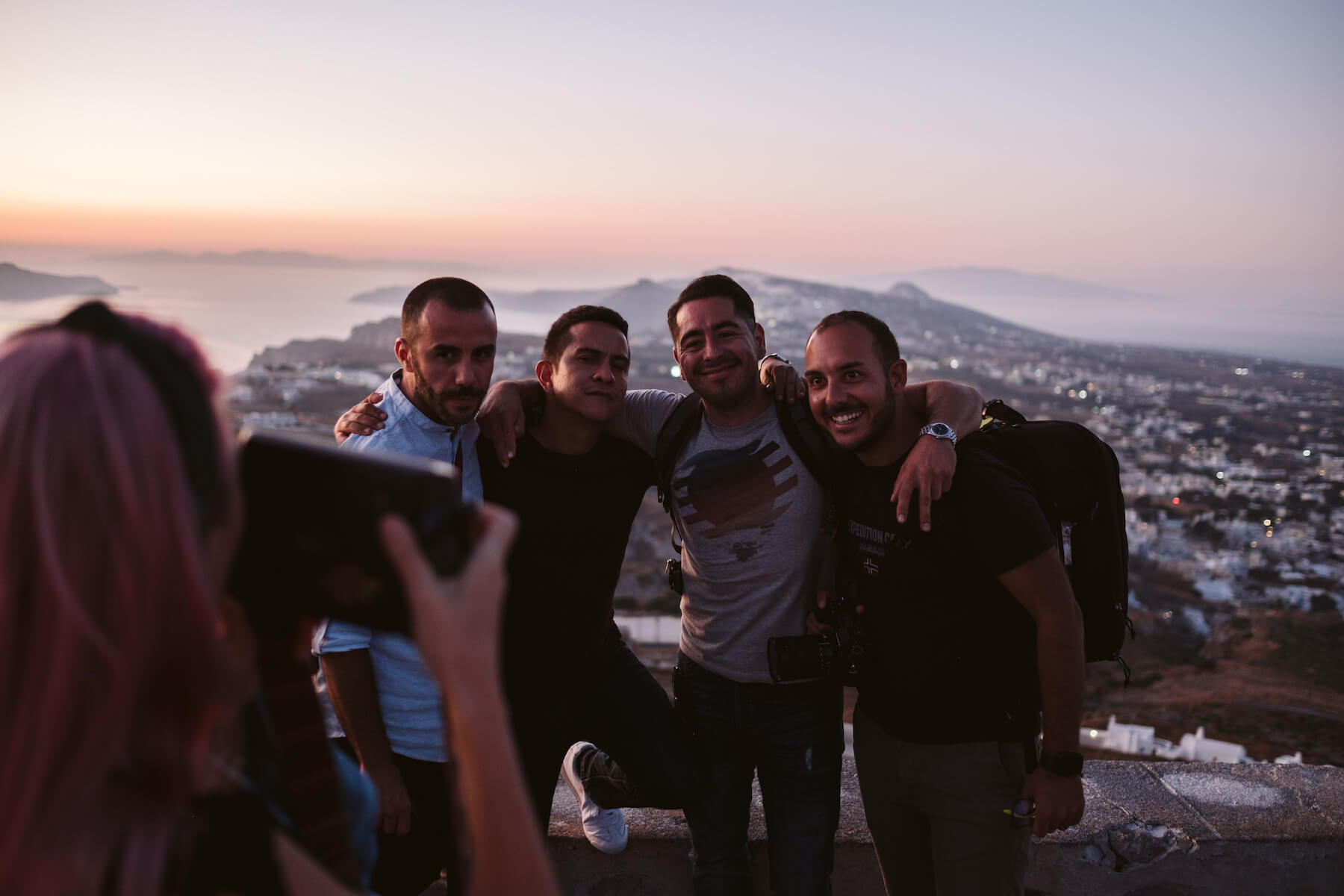 Group of men posing for a photo in front of the view in Santorini, Greece