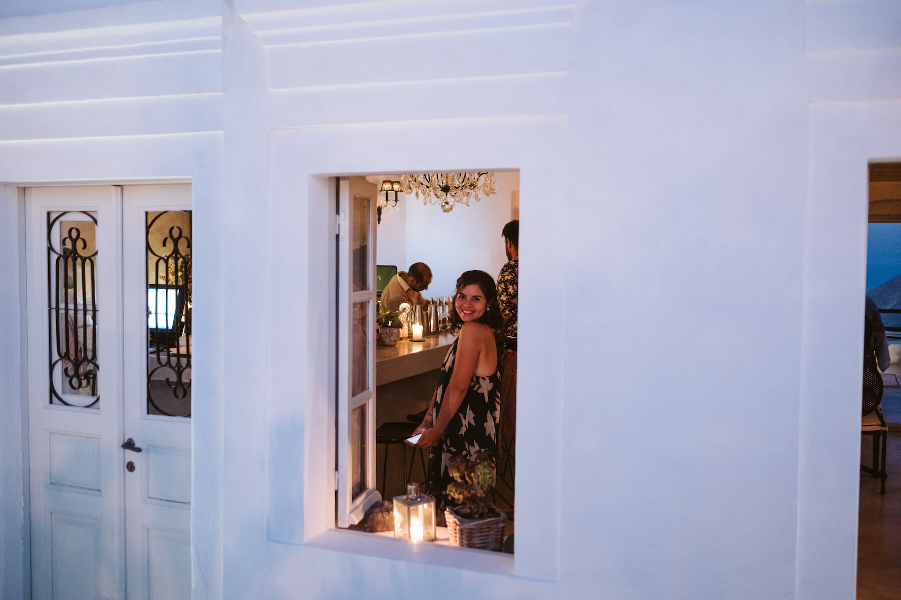 A woman smiling from a window at a restaurant in Santorini, Greece