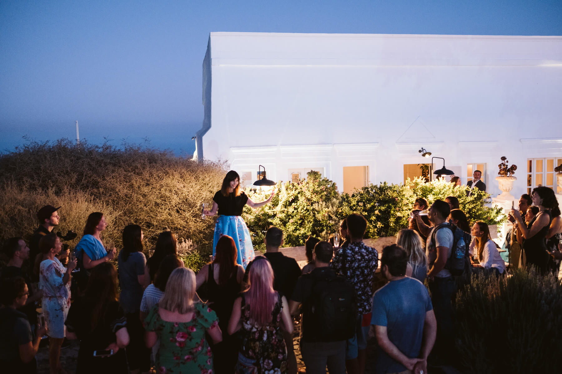 A woman making a speech to a group at a restaurant in Santorini, Greece