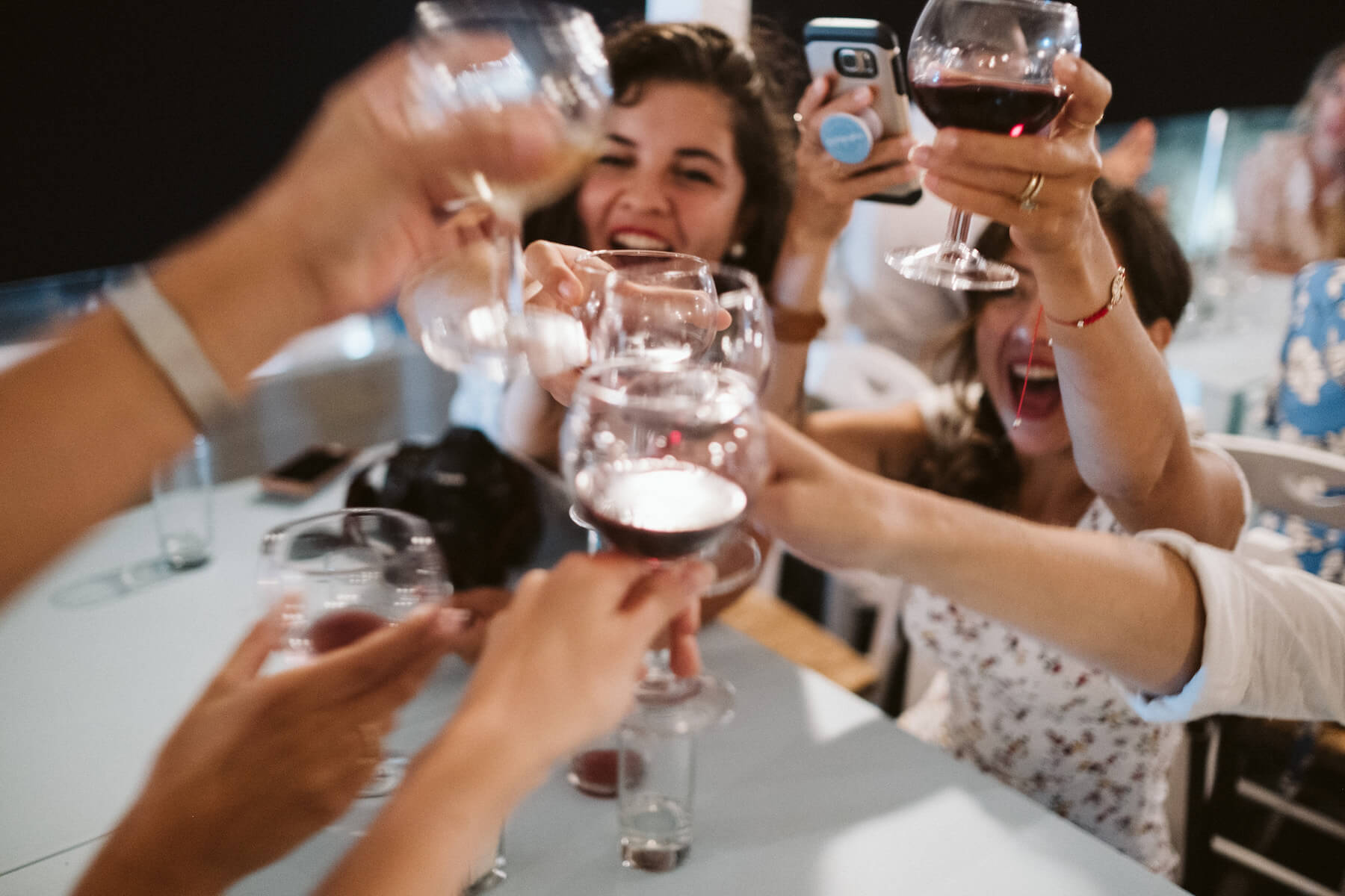 People raising their wine glasses while having dinner in Santorini, Greece