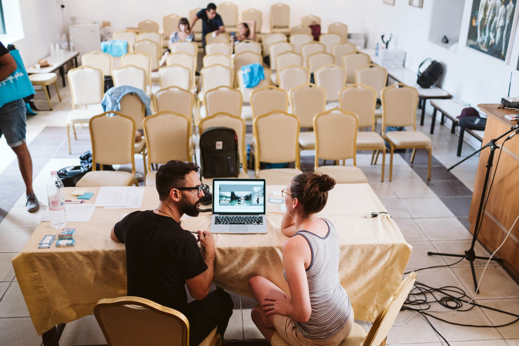 Two people talking around a laptop screen in a conference room in Santorini, Greece
