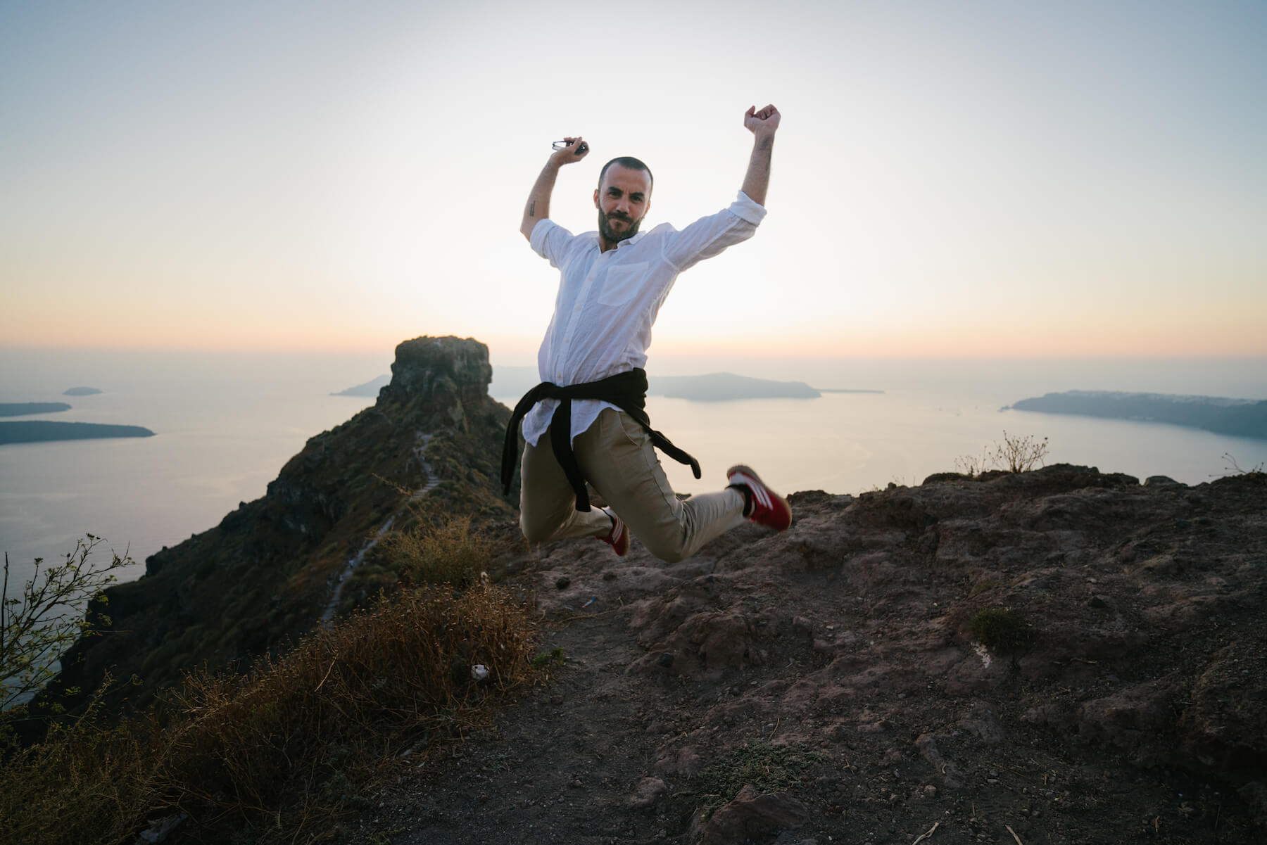 A man jumping for fun at Skaros Rock in Santorini, Greece