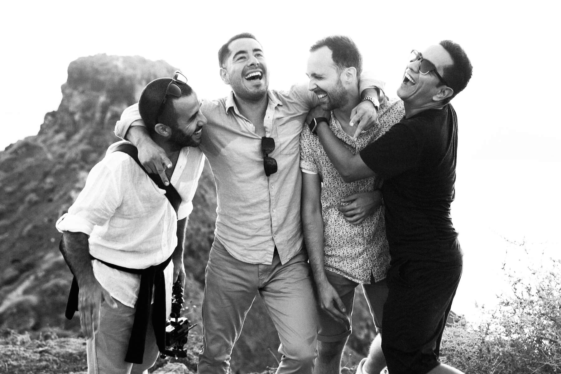 Four men laughing and hugging in Santorini, Greece