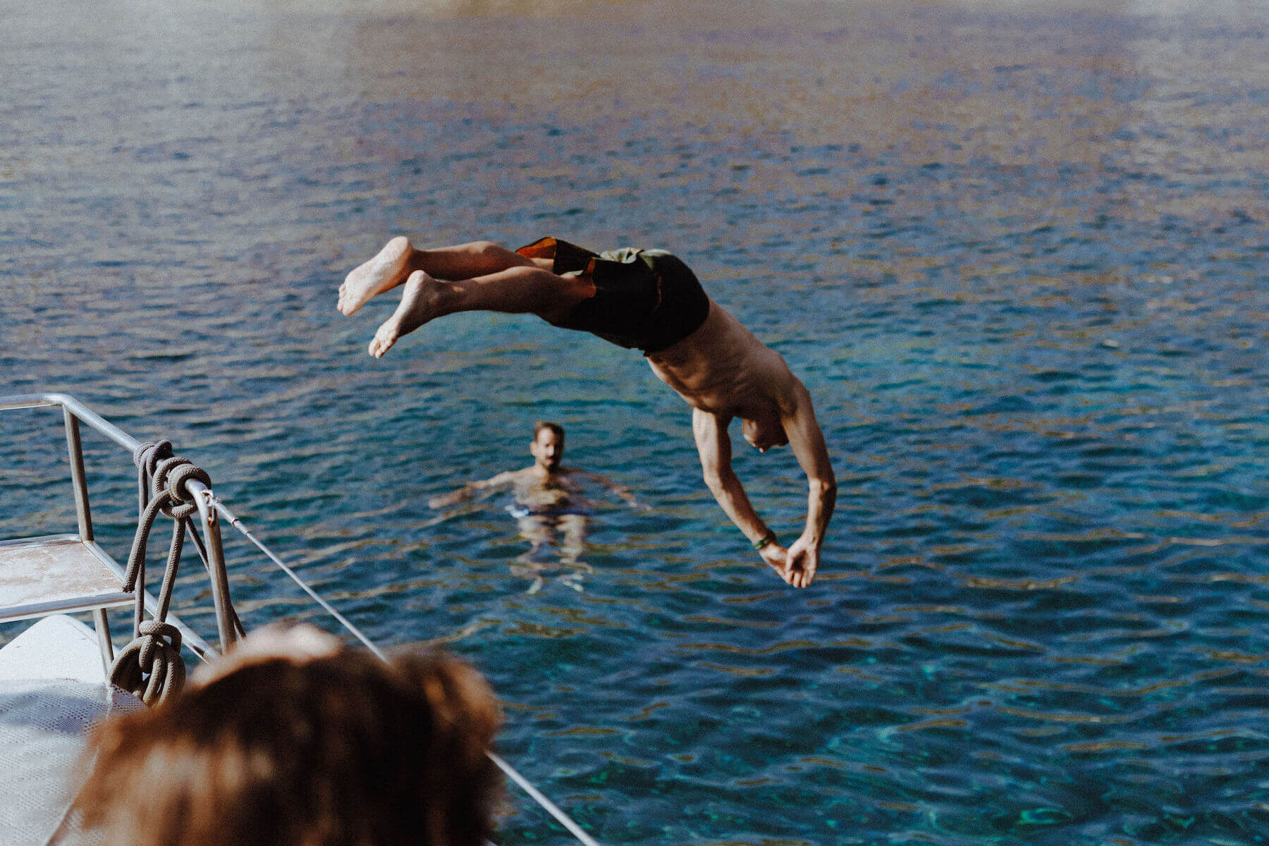 People diving off a boat in Santorini, Greece