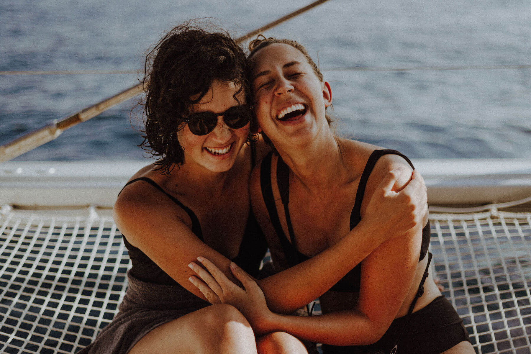Two woman hugging and laughing on a boat in Santorini, Greece
