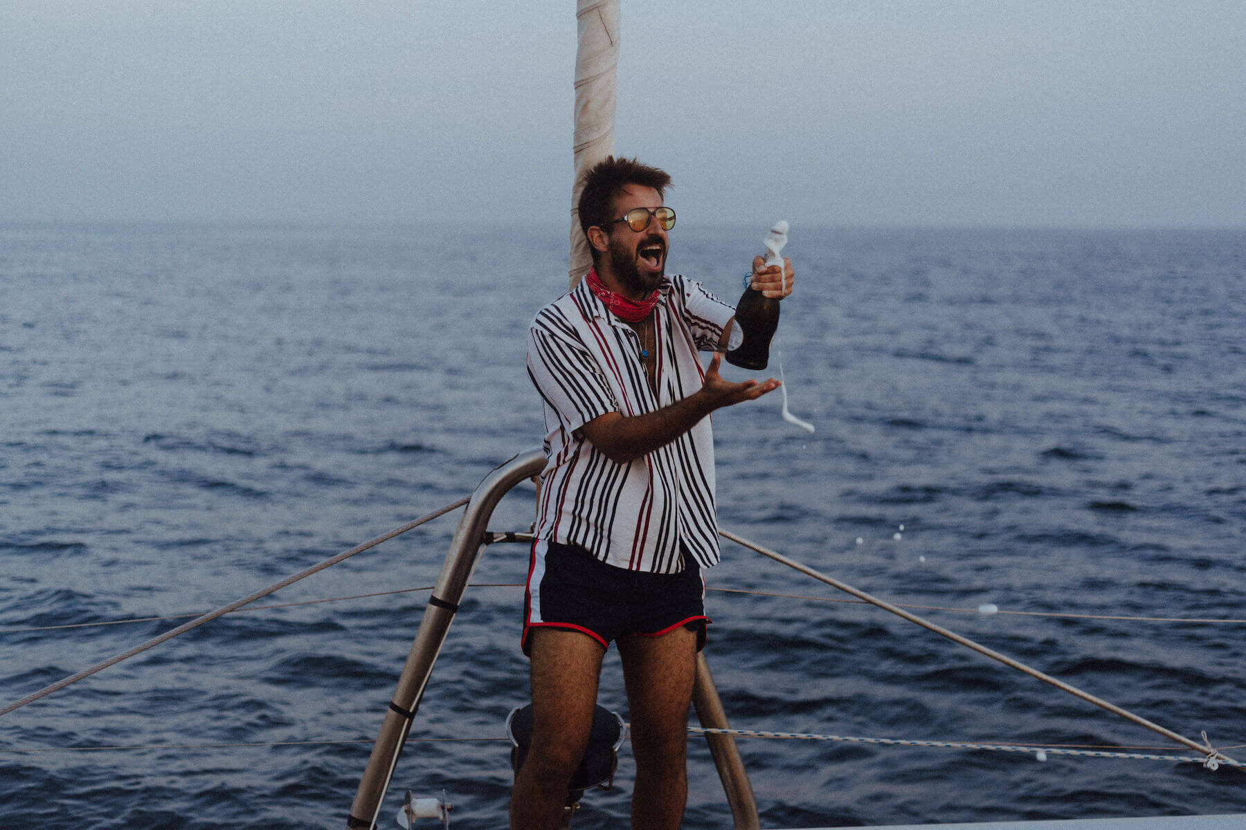 A man opening a bottle of champagne on a boat in Santorini, Greece