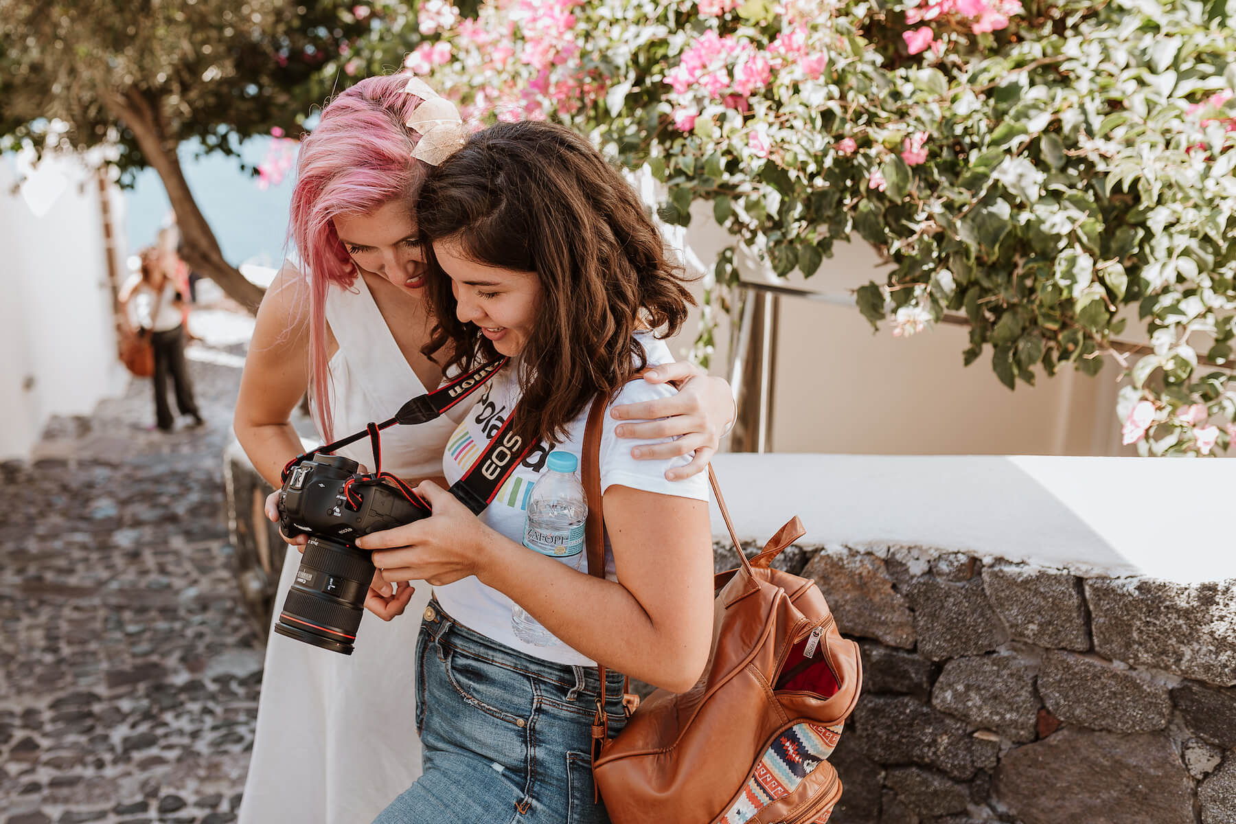 Two photographer looking at the back of a camera in Santorini, Greece.