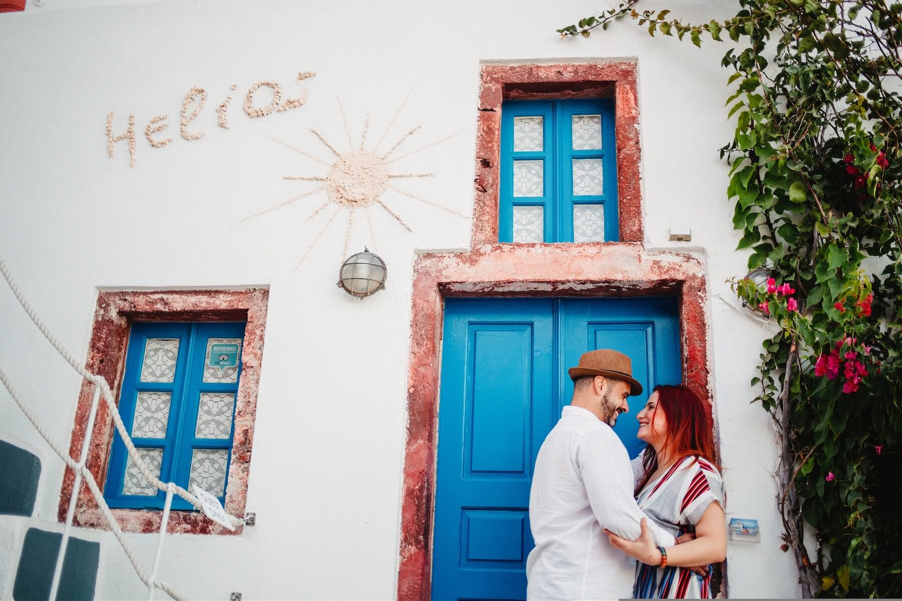 A couple embracing by a colourful wall in Santorini, Greece