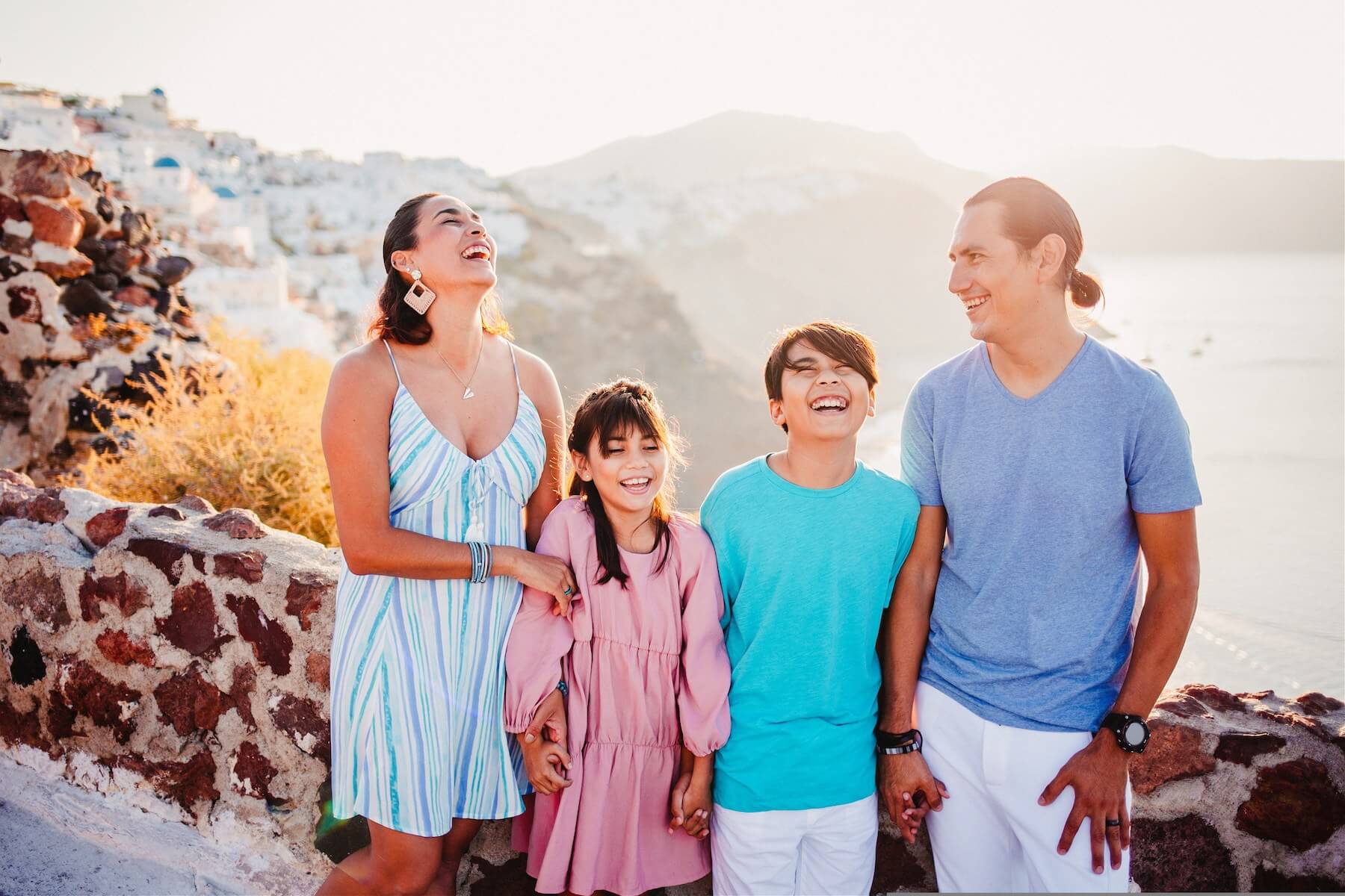 Family laughing in front of a sunrise vista in Santorini, Greece