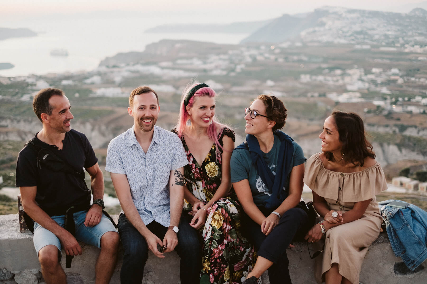 Group of people sitting and smiling in front of the view in Santorini, Greece