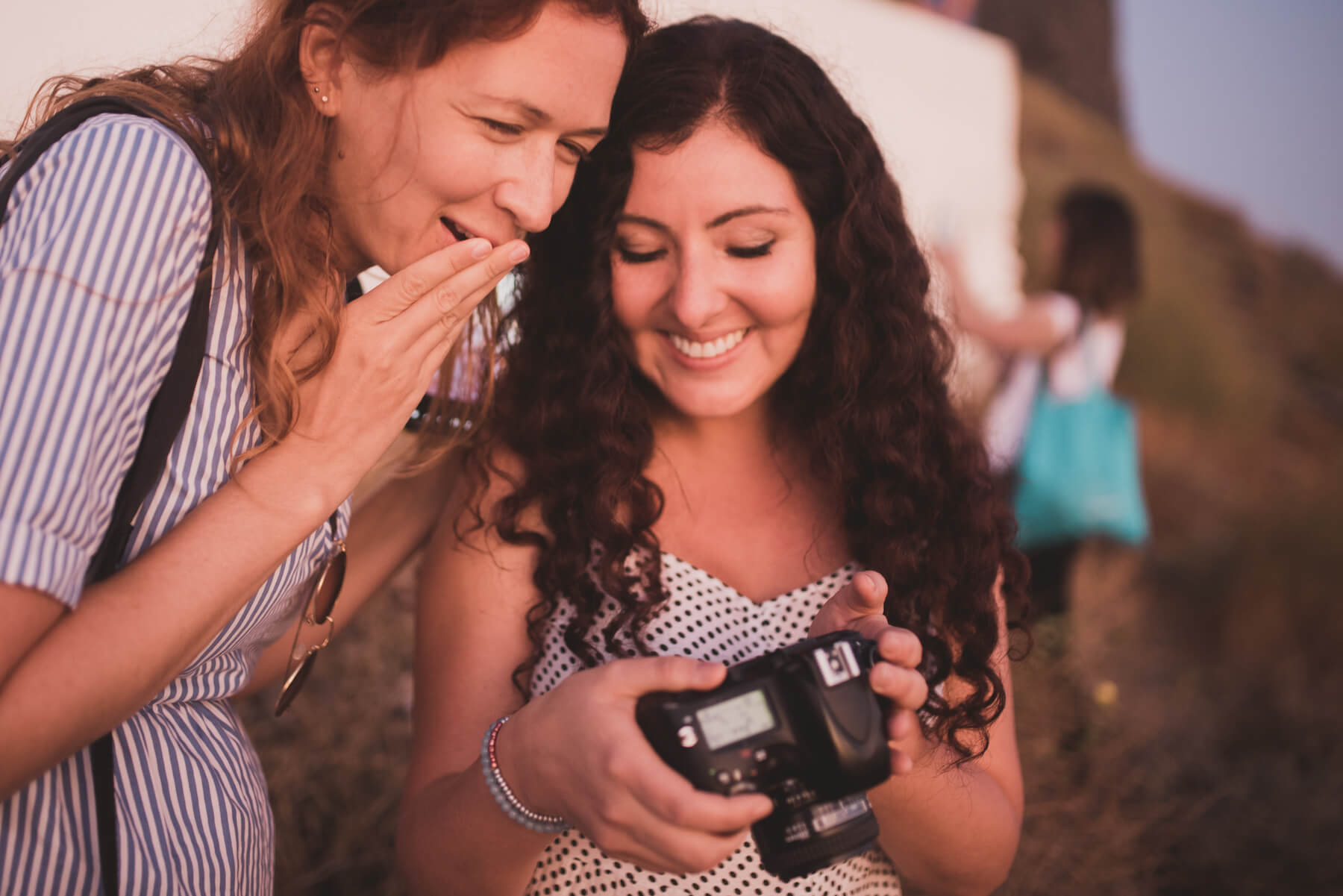 Two women looking at a back of a camera in Santorini, Greece