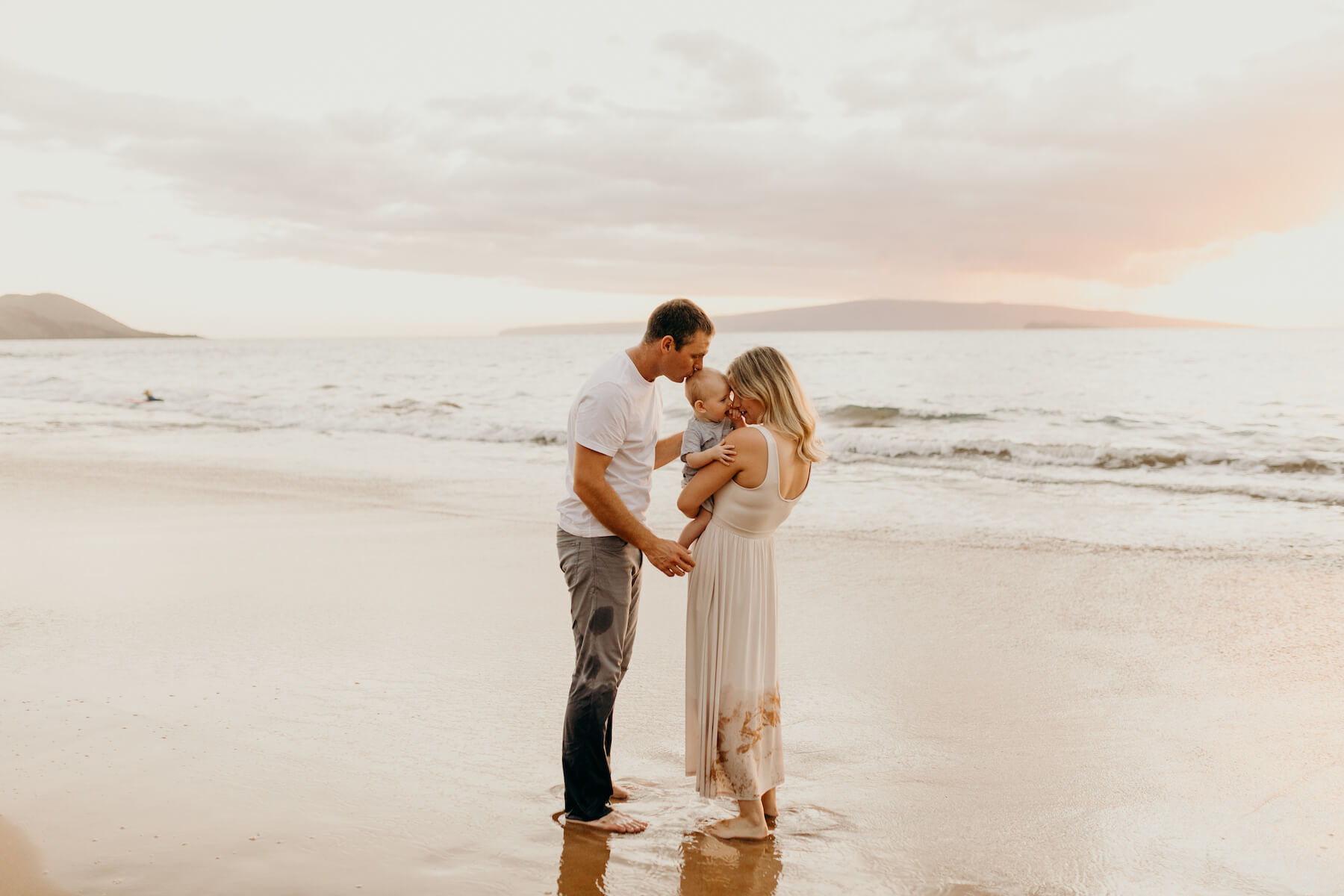 family of three with a baby boy, holding the child and playing on the beach in Maui, Hawaii