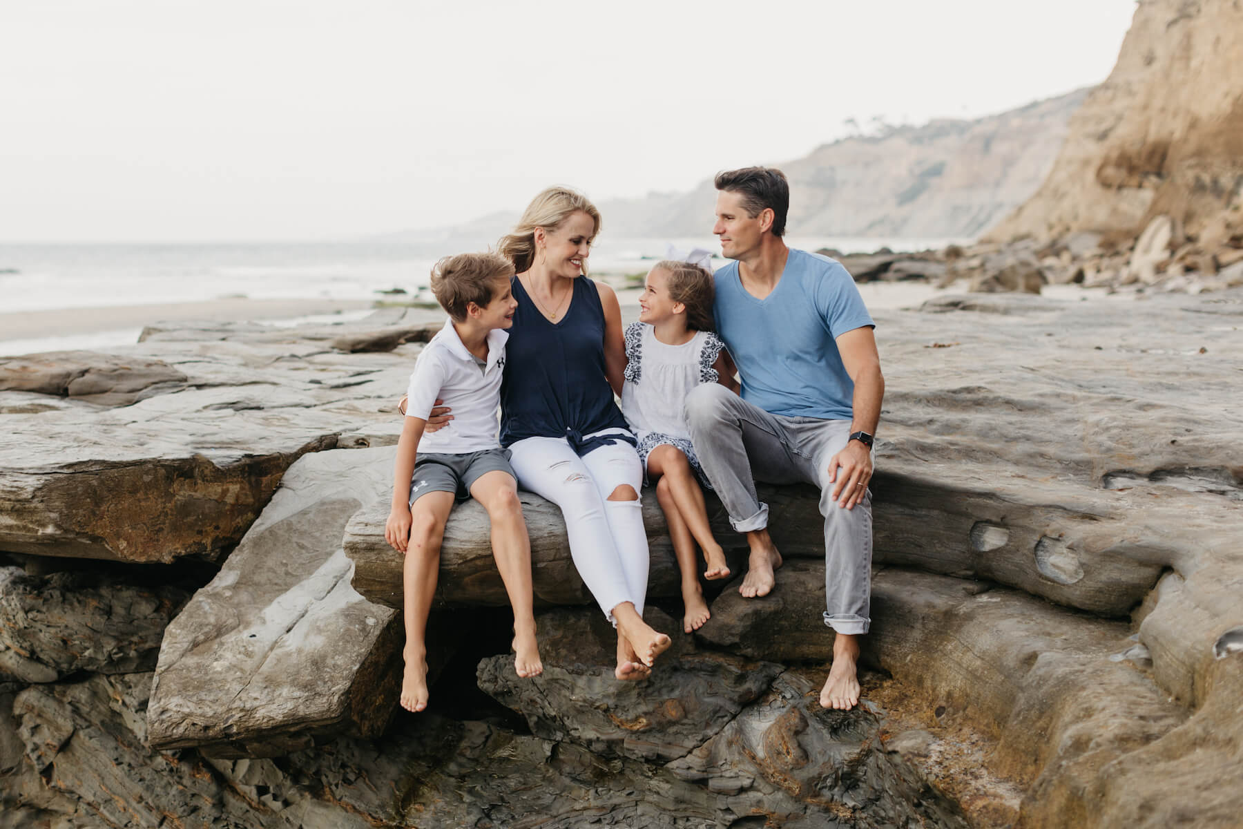 family of four sitting on a rock on the beach in San Diego, California