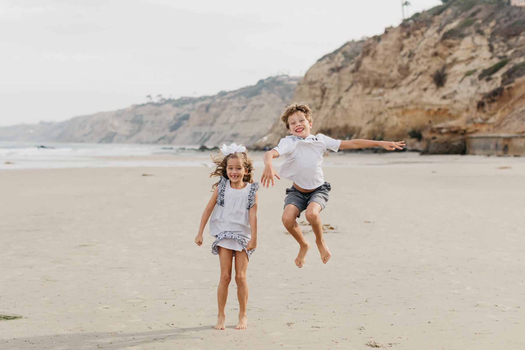 brother and sister on the beach, jumping in San Diego, California