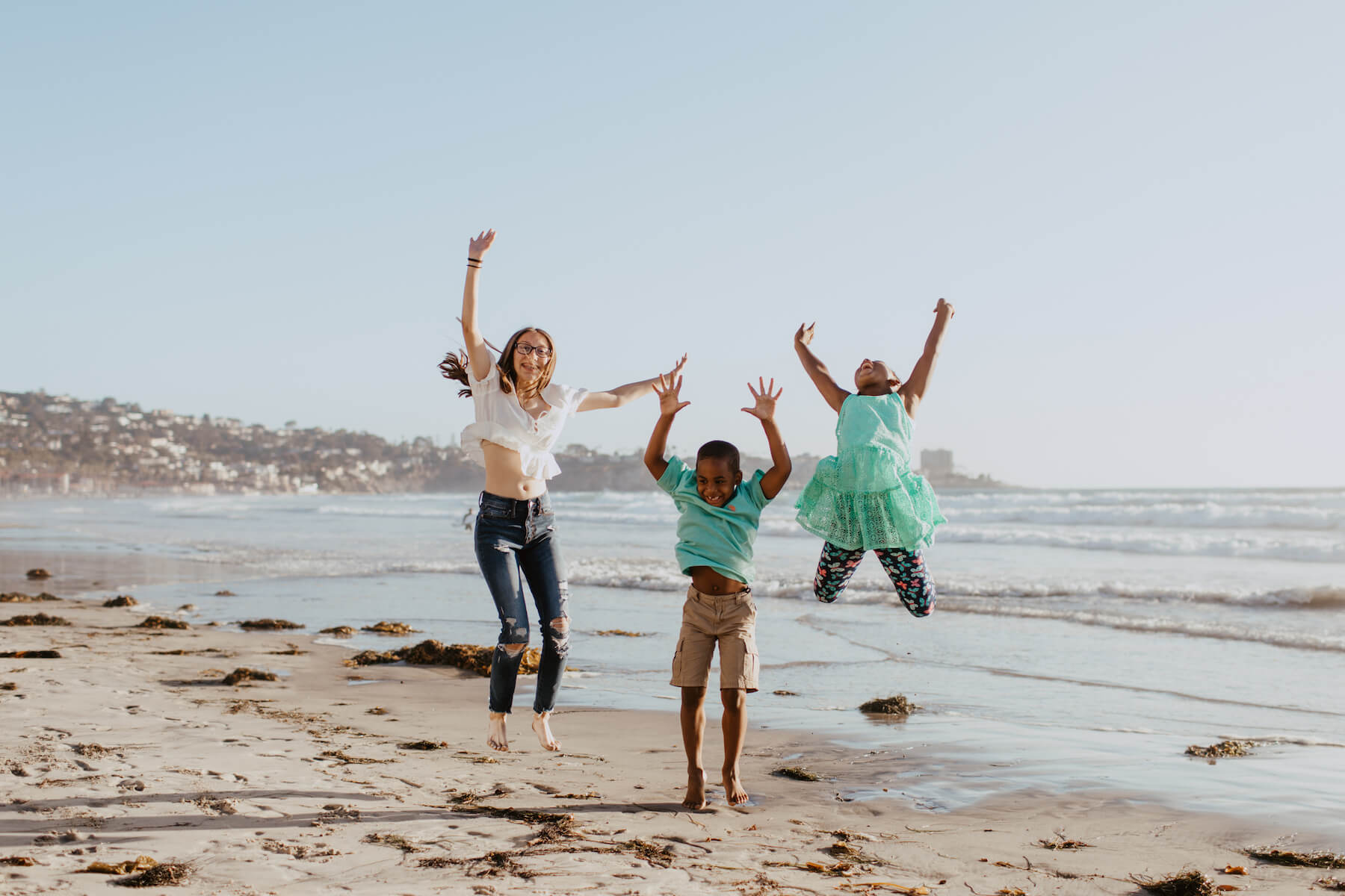 3 kids jumping on the beach in San Diego, California