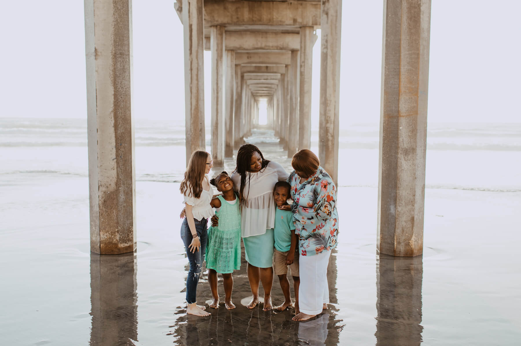A family standing under the boardwalk on the beach in San Diego, California